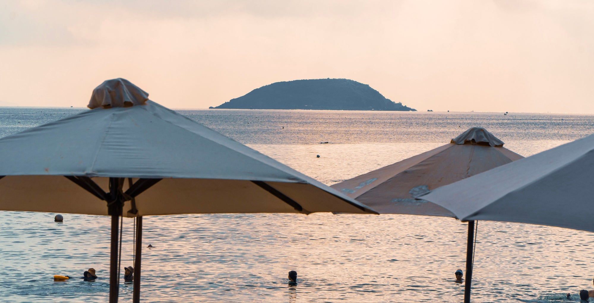 Beach umbrellas with a scenic view of the ocean and distant island.